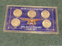 Front view of the JFK 30th Anniversary Silver Clad Coin Set showing five coins from 1965 to 1969 in blue and clear plastic hard case.