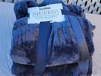 Folded Kirkland Queen Plush Blanket with packaging showing size and brand on label