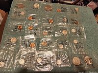 Wide view of lot showing multiple uncirculated US silver coins in original mint packaging arranged on green towel.