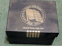 Blue storage box with silver text 'Twenty Five Years 1968-1992 United States Coin Sets' and an American flag design on top.