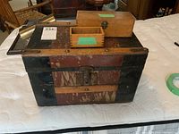 Photo showing the vintage trunk with two wooden boxes placed on top. Trunk has metal corners and rivets, wood panels show heavy wear.