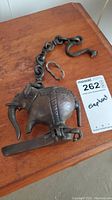 Full view of cast bronze elephant hanging oil lamp with chain and hook showing broken leg piece and detailed engravings.