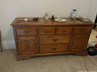 Wide front view of the full Vilas maple buffet showing two cabinets on each side and three drawers in the center with their metal handles.
