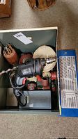 Photo showing the Job Mate corded drill along with various attachments like sanding disks and buffing wheels inside a metal drawer.