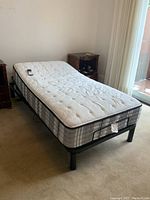 Angled view of bed frame, mattress and remote control