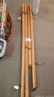 Four wooden stair hand rails laid on carpet floor, showing varying lengths and attached metal wall mounts.