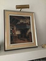 Framed painting with matte and attached display light mounted on wall