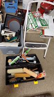 Various paint rollers and roller covers, caulking gun, and roller frames inside open black toolbox