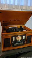 Open lid showing the vinyl record turntable inside the wooden cabinet with 'VICTROLA' on inner lid.