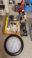Overview of all items including hand tools, measuring instruments, chemicals, and wall clock on floor