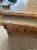 Open drawer of the wooden washstand showing the inside and original hardware on the drawer front.