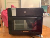 Front view of the CalmDo air fryer toaster oven with closed door and brand name visible.