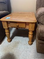 Front view of the wood end table showing the flat top and thick turned legs.