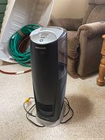 Full view of black and silver Honeywell Quiet Care humidifier standing on carpeted floor with visible power cord and surrounding furniture