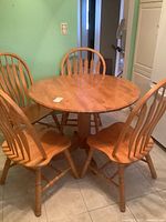Full view of round wood table with four matching chairs around it
