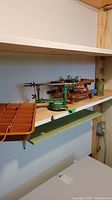 Shelf with green metal apple peeler and corer mounted on wood base, and picnic table-shaped salt and pepper shaker set in holder.