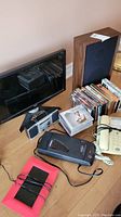 Photo of 20-inch Acer monitor, DVDs, CDs, beige corded telephone, VHS rewinder, digital picture frame, radio and speaker on floor
