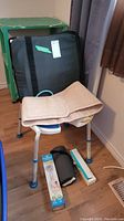 Photo showing the plastic shower chair, back support belt, thick cushion in black case, and additional small boxed items on floor.