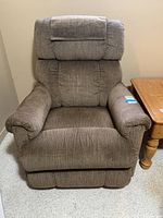 Front view of brown La-Z-Boy rocking recliner chair with padded arms and headrest cover.