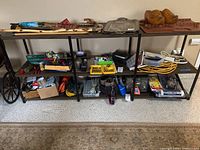 Full view of metal shelving unit with assorted tools, extension cords, and office supplies on middle shelf.