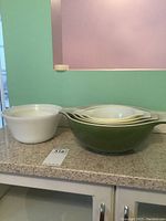 Green and yellow Pyrex nesting bowls stacked, with white nesting bowl beside.