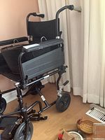 Full side view of black Airgo wheelchair including the wire basket and foot rests.