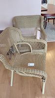 Two beige plastic wicker chairs with metal frames, showing some wear and wicker coming apart.