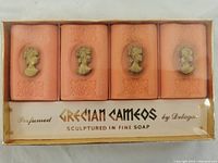 Four perfumed fine soap bars with sculptured cameo reliefs on peach-colored soap, sealed in original clear plastic box with gold text labeling.