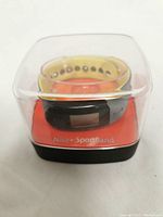 Clear plastic case containing Nike+ SportBand with black device and yellow ventilated strap, displayed on orange insert labeled 'Nike+ SportBand'.