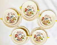 Top view of five tea cups placed on their matching saucers showing floral bird motif inside cups and lattice pattern on saucers.