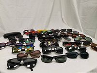 Full group of approximately two dozen sunglasses laid out in rows