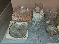Full view of all 10 glass collectible items, including etched and cut glass bowls, plates, and candle holders.