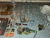 Wide view of clear drinking glasses, some with colored decorations, plus kitchen utensils and miscellaneous glassware