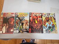 Four issues of Flash Comics laid out showing distinct cover designs featuring the comic's protagonist and thematic elements regionally from bright action scenes to darker covers.