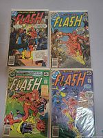 Photo of four Flash comics with colorful covers laid out on a surface, showing characters and comic details including price and DC logo.