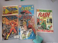 Five Flash comic books, front covers shown spread out on a table.