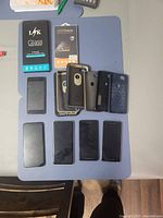 Overview photo showing four Google cell phones face up, six phone cases stacked above phones, and two unopened glass screen protector packages on table, all arranged neatly.
