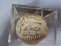 Close-up of signed baseball showing multiple autographs inside clear acrylic display case