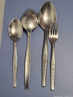 Four silverplate serving pieces including a serving spoon, ladle, large serving spoon, and serving fork.