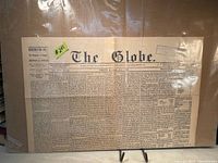 Full broadsheet front pages of The Globe in protective sleeve displayed on stand