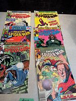 Top-down photo showing six vintage Marvel The Amazing Spider-Man comic books arranged side by side, covers visible featuring Spider-Man, The Black Cat, and various characters.