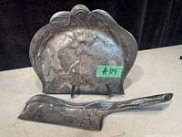View showing crumb tray with floral design and matching brush from front angle.