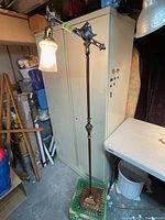 Full view of antique floor lamp against storage cabinet, showing height and base details.