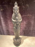 Front view of one carved wood Monkey King statue showing detailed facial features and traditional Asian attire.