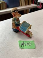 Photo shows the vintage Popeye toy from the 1960s including the figurine character and scooter accessory, placed on a white surface with a green label #143.