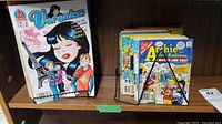 Shelf with various Archie and Veronica comic books, including a large-sized Veronica comic and several other Archie comics in upright stack