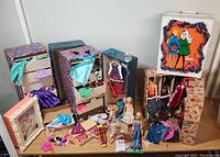 Overview of entire lot on table showing wardrobe cases, dolls, clothing, shoes and framed print