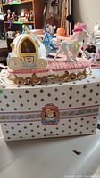 Full side view of the music box showing pumpkin carriage, horse, coachman, base design and original box underneath.