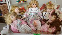 Basket containing five porcelain dolls with various dresses and hairstyles, one with an identification tag