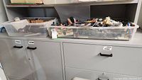 Bins on cabinet with assorted Lego and Playmobil pieces visible